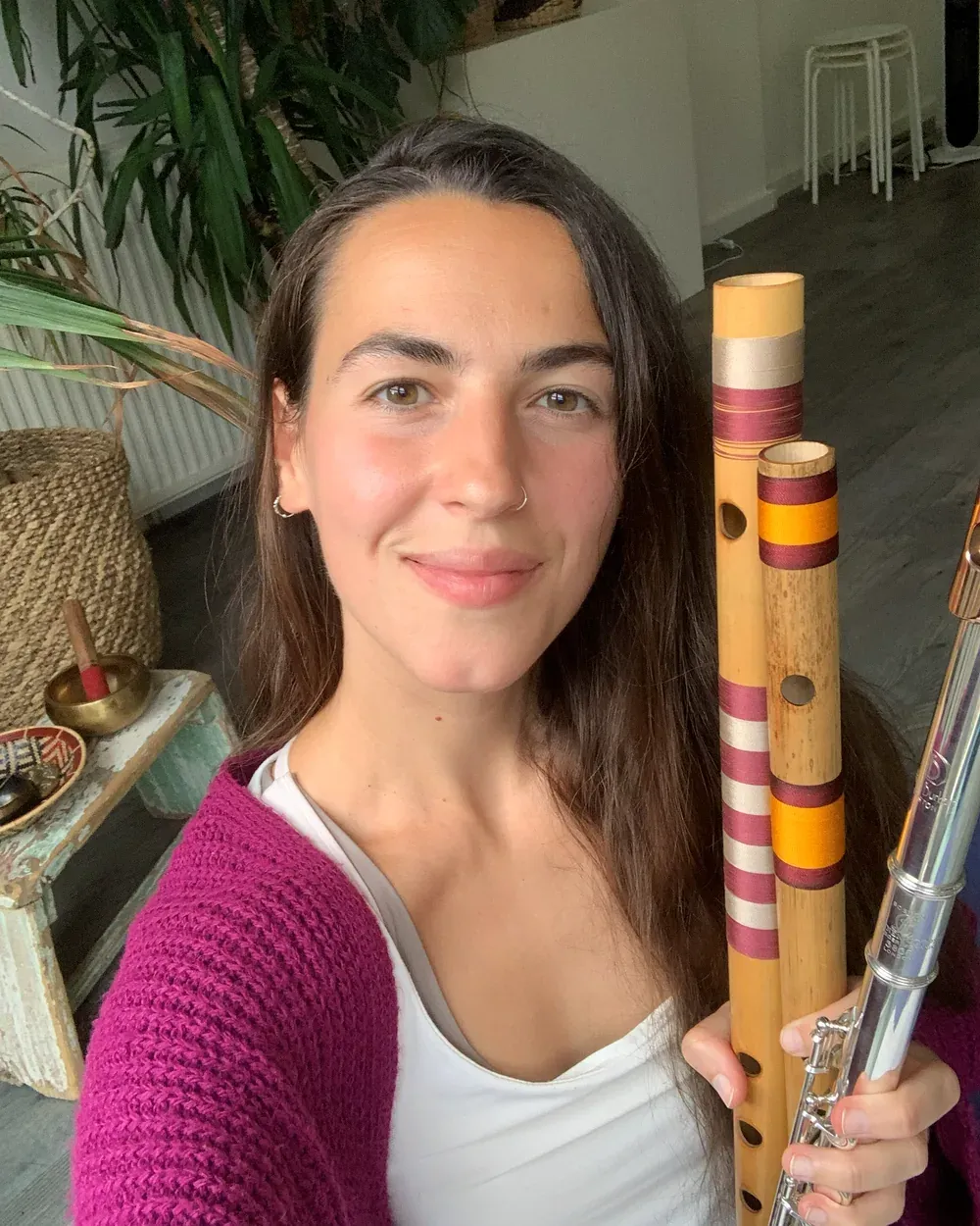 Juani Justicia García smiling warmly, holding a bamboo flute and a silver concert flute